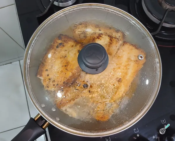 Cozinhando os filés de linguado com água em frigideira tampada