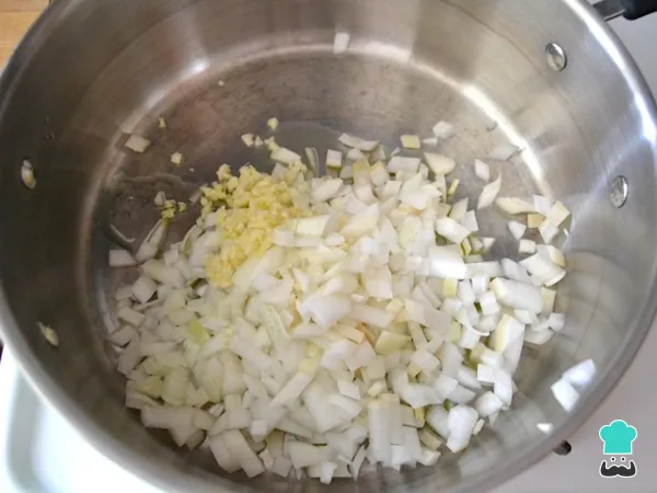 Cebola e alho refogando em azeite na panela para o frango cozido