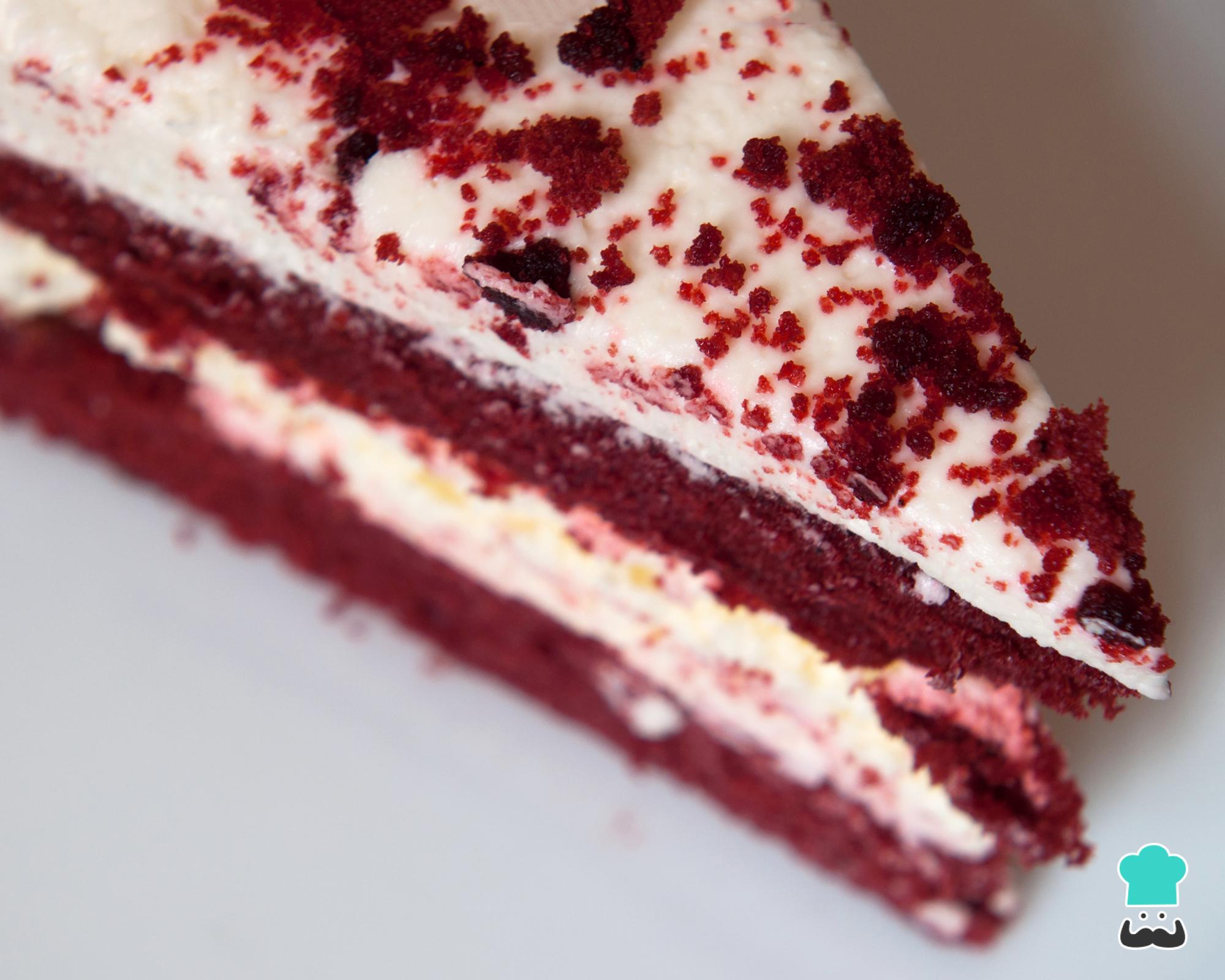 Bolo de veludo vermelho com cereja em um prato branco e uma xícara de café